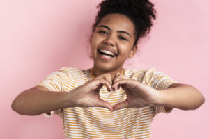 woman smiling while making a heart shape with her hands
