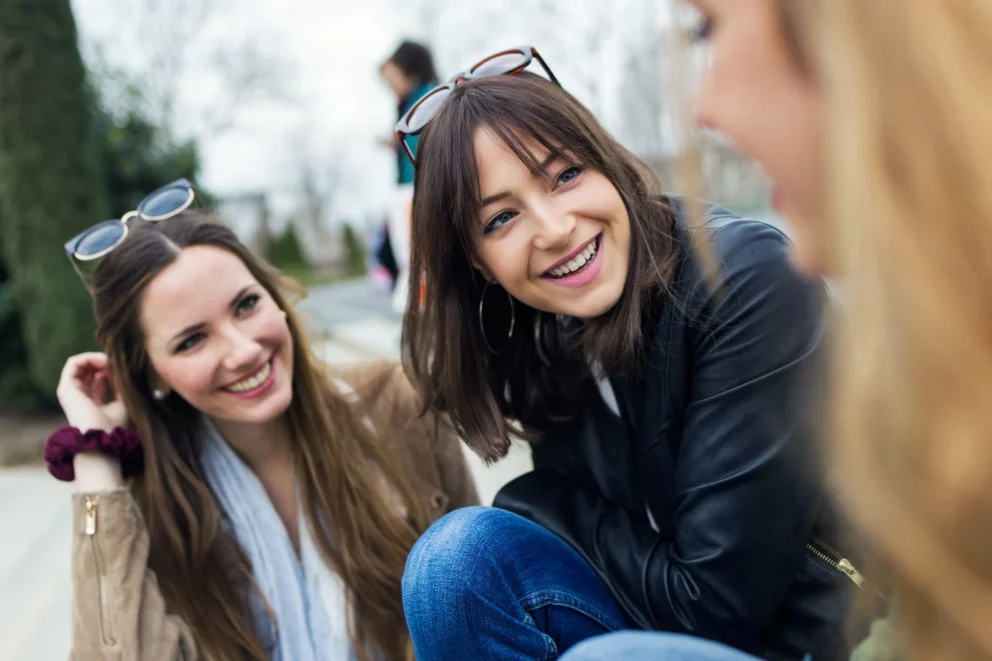 three young women talking and laughing in the street